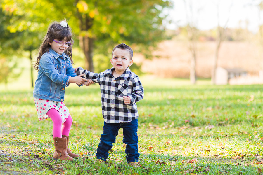 big sister pulling crying baby brother