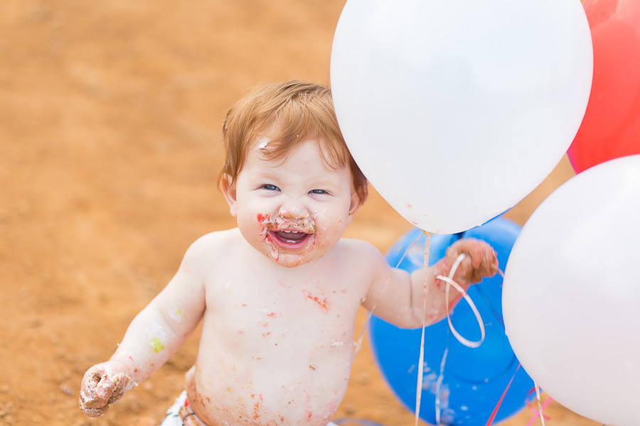 messy baby boy laughing holding balloons