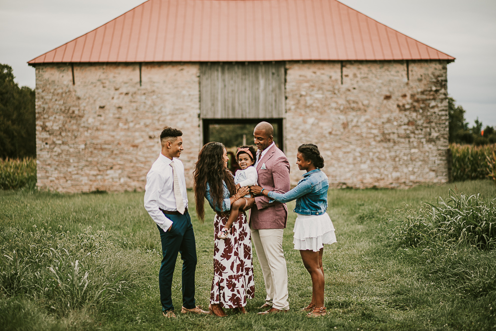 family of five in front of stone barn