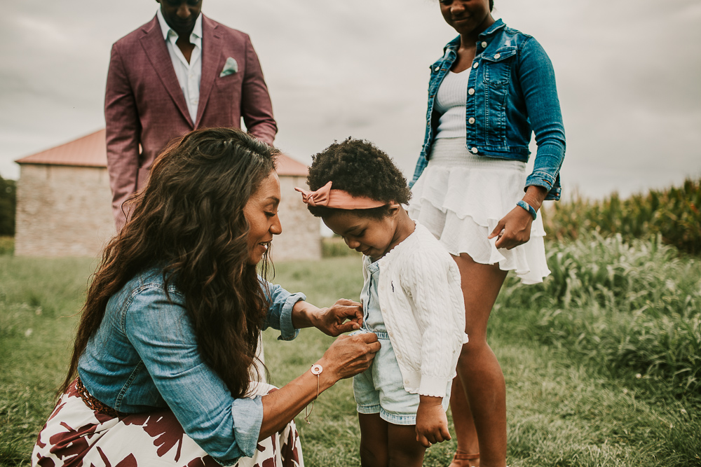 mom buttoning daughters sweater