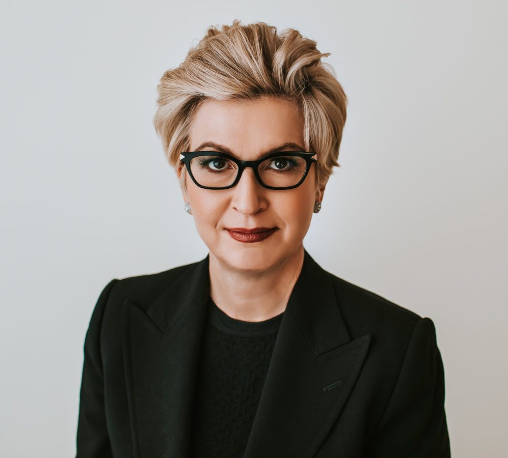 blonde woman in black glasses headshot