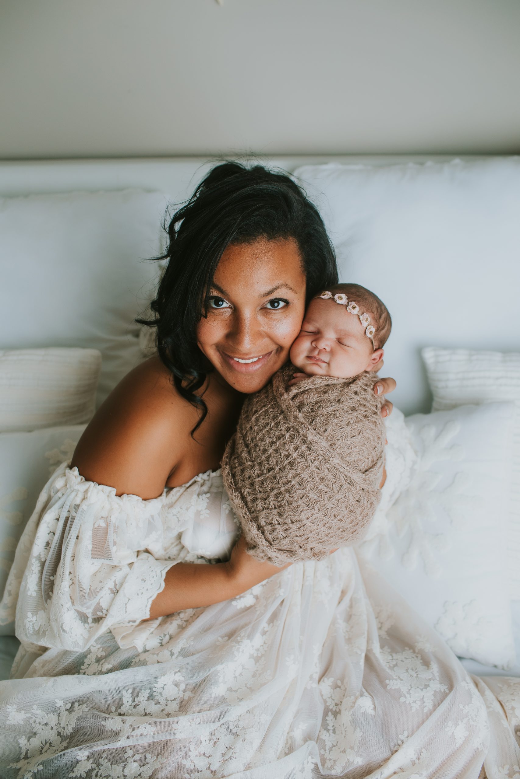 mother posing with newborn girl swaddled