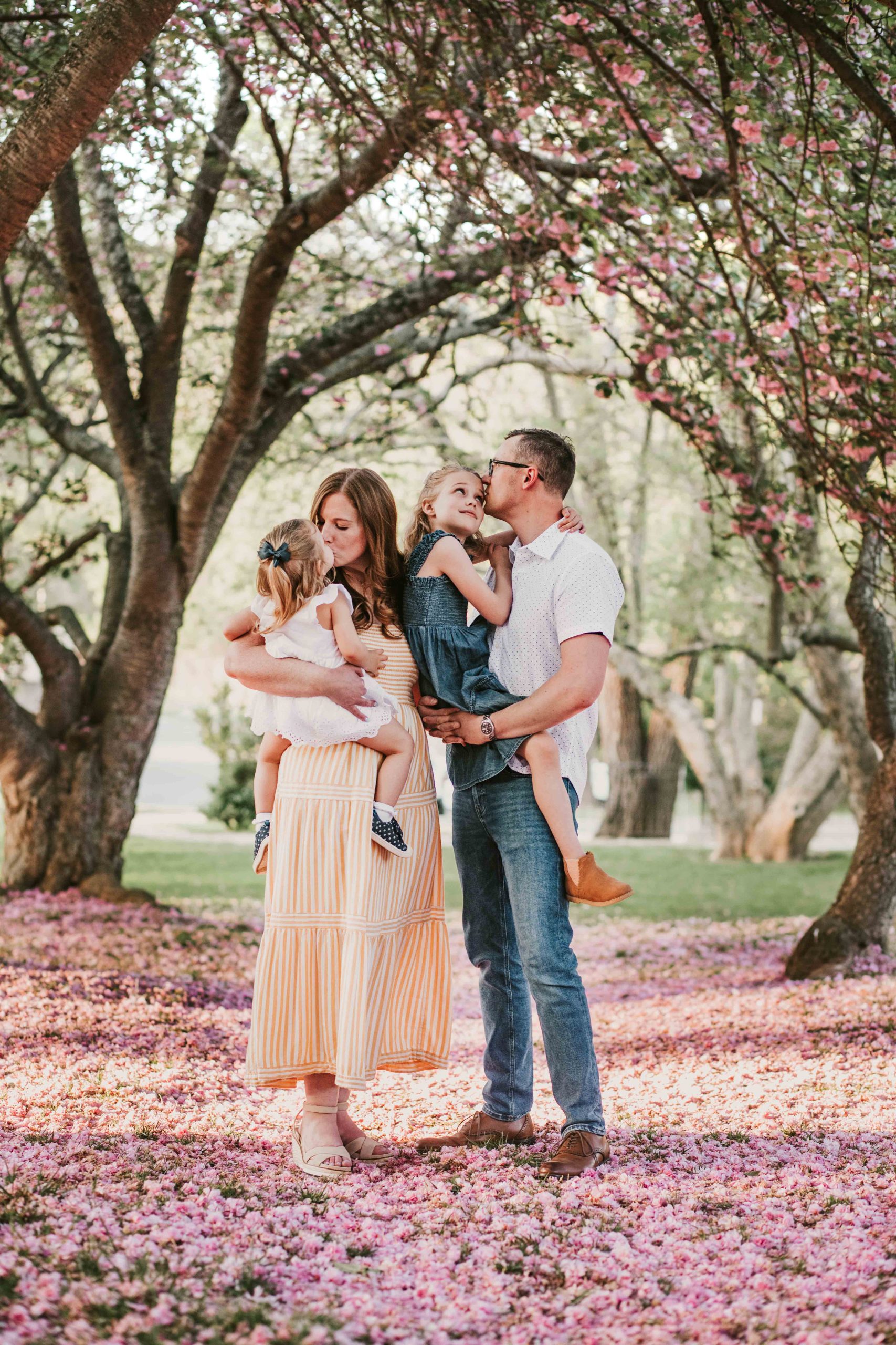 family under pink cherry blossom tree