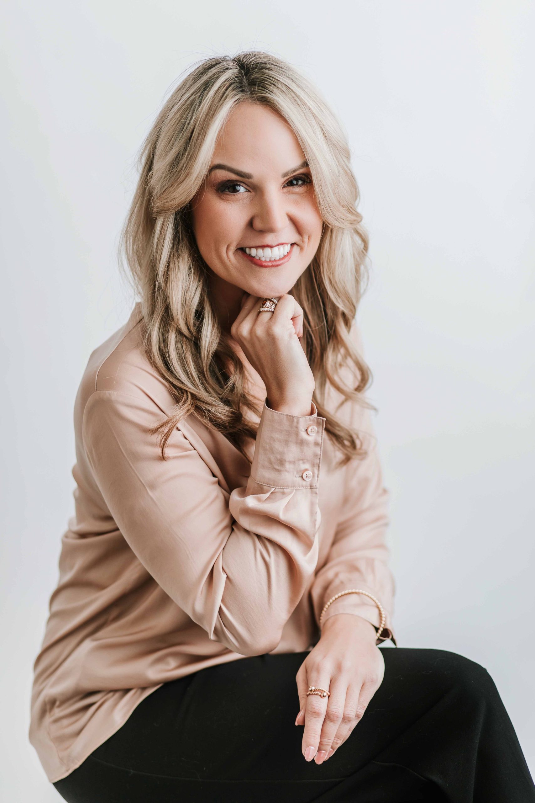blonde woman in pink blouse headshot on white studio backdrop