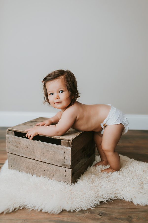 baby standing up holding onto crate