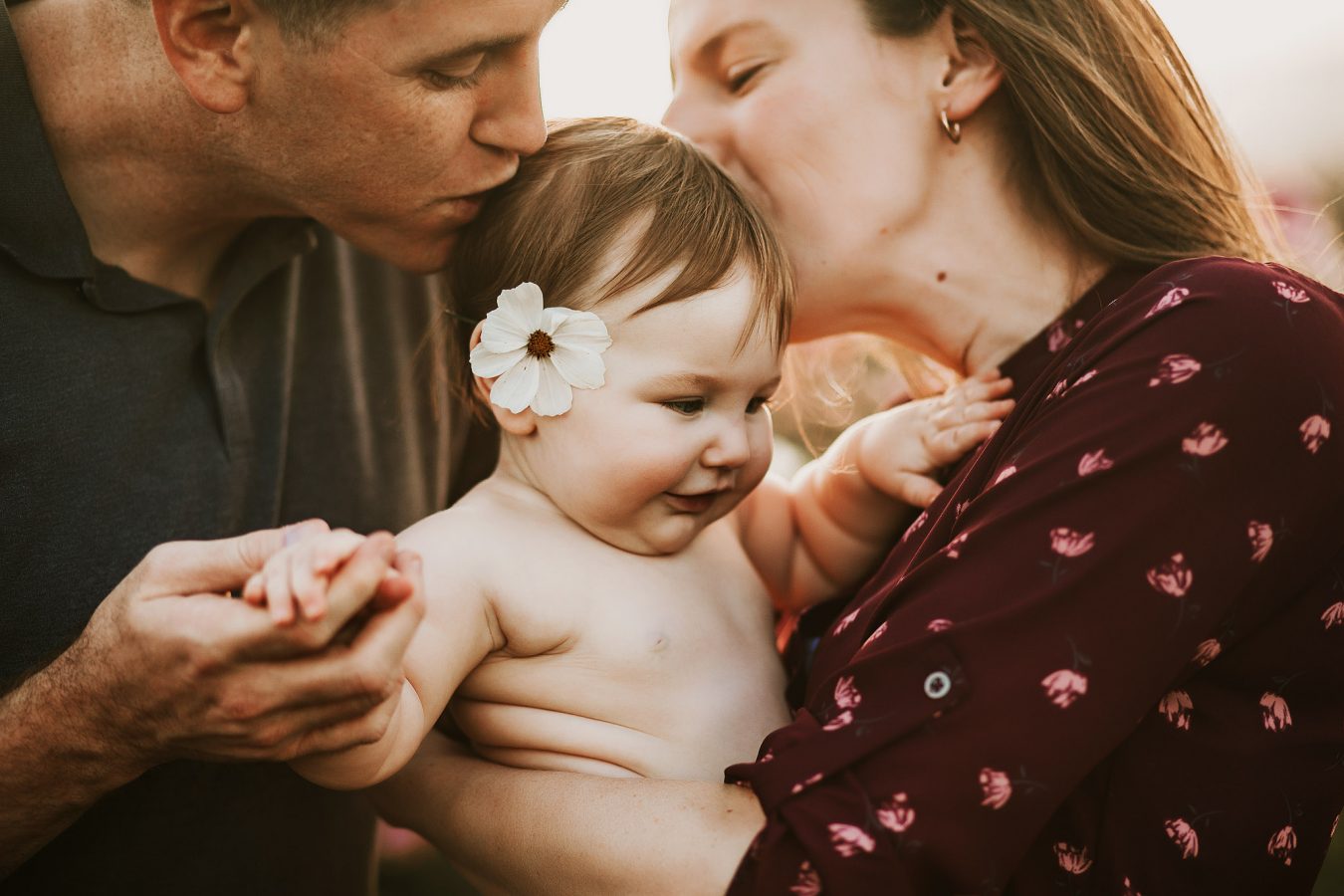 parents kissing chubby baby girl