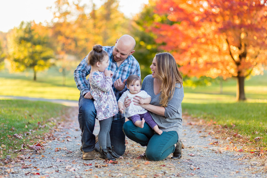 family of four in front of bright colored foliage