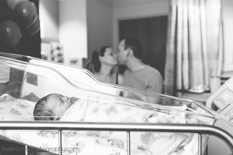Mom and dad kissing while infant sleeps