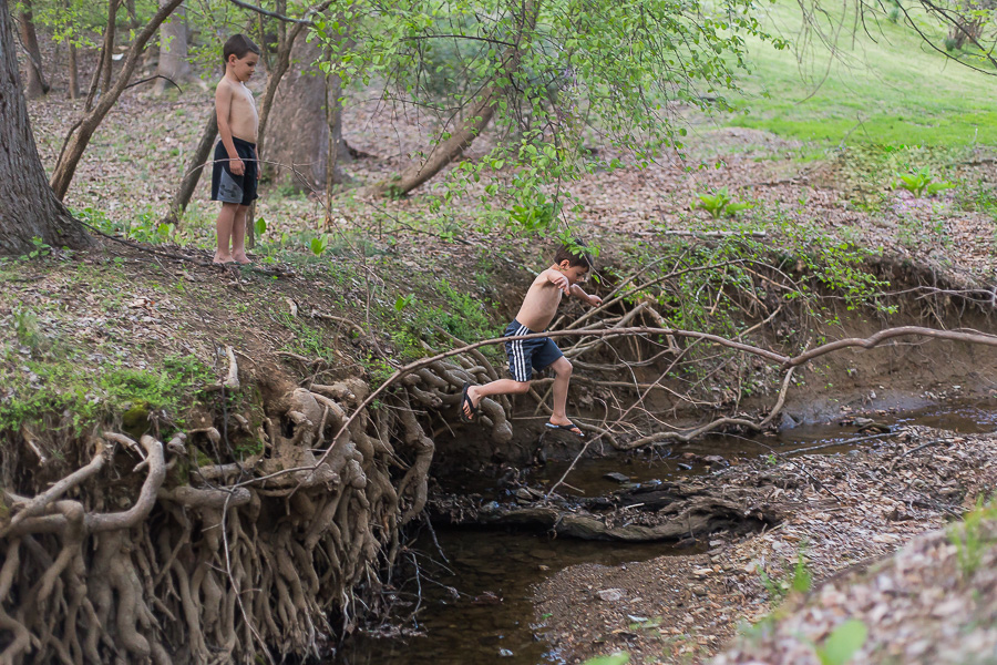 boy jumping off cliff at creek