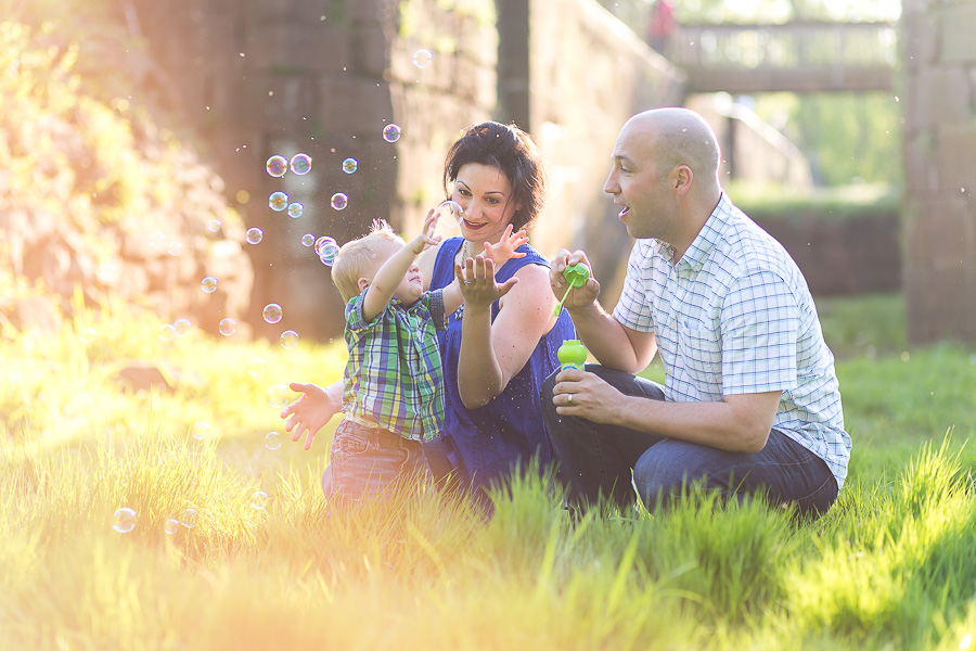 family sitting in grass with golden light and bubbles