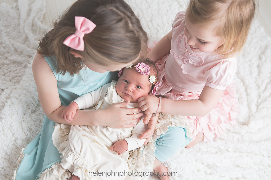Newborn baby being held by older siblings