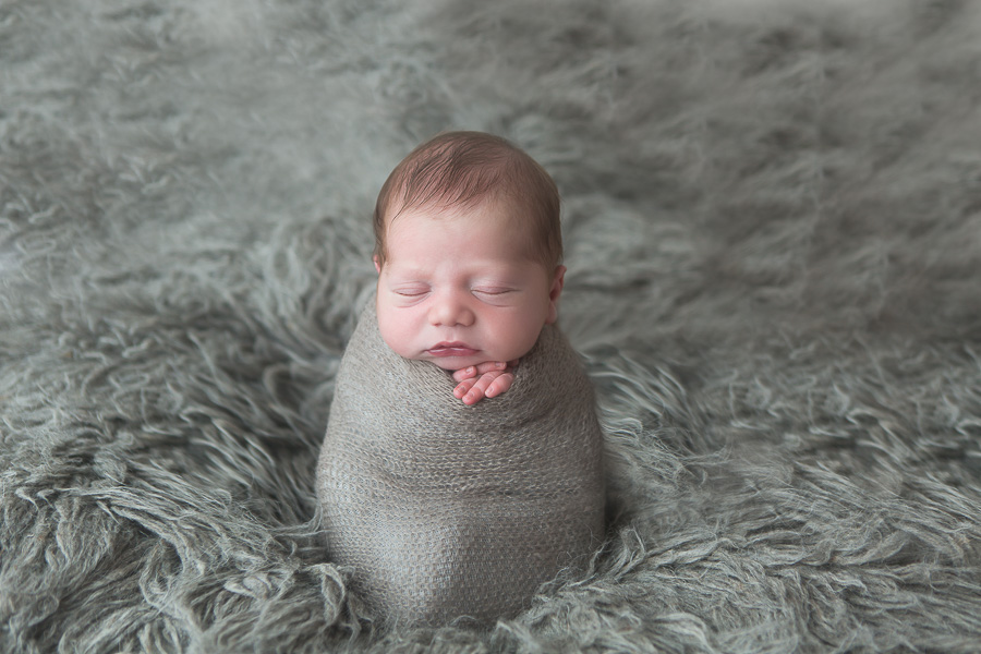 newborn boy on grey flokati potato sack