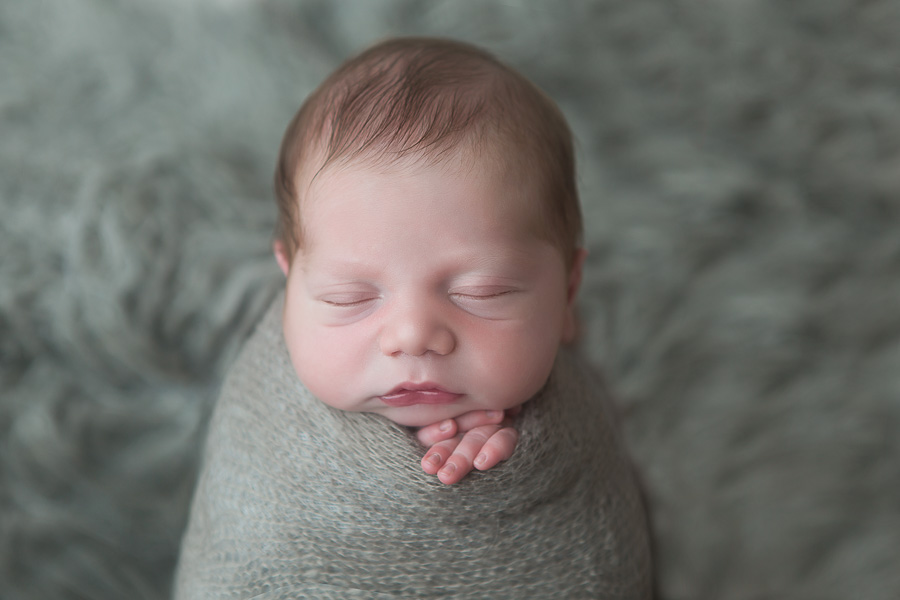 adorable newborn baby boy in potato sack pose on grey