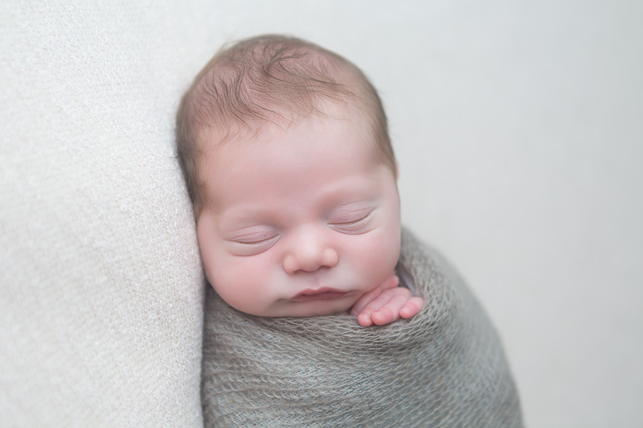close up of newborn boy wrapped in grey