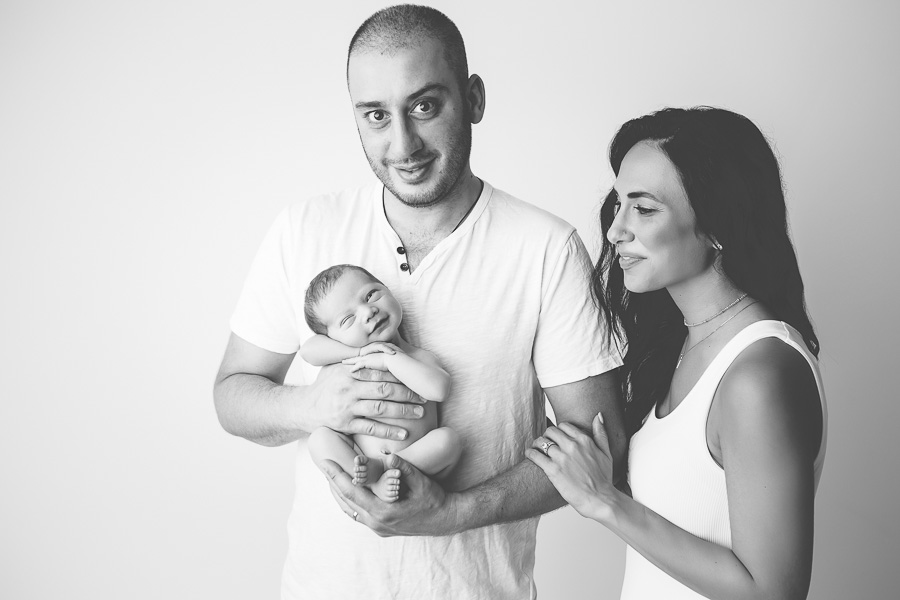 B&W image of newborn laughing with parents