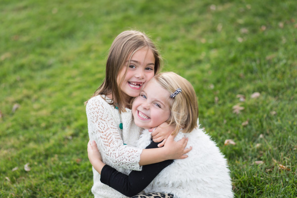 little girl sisters hugging in the grass