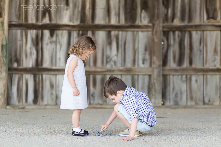 young brother and sister playing inside barn