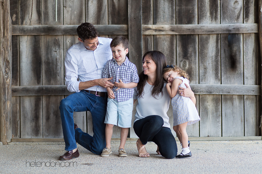 family of four laughing in barn