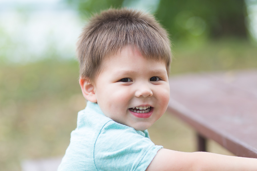 two year old boy smiling outdoors