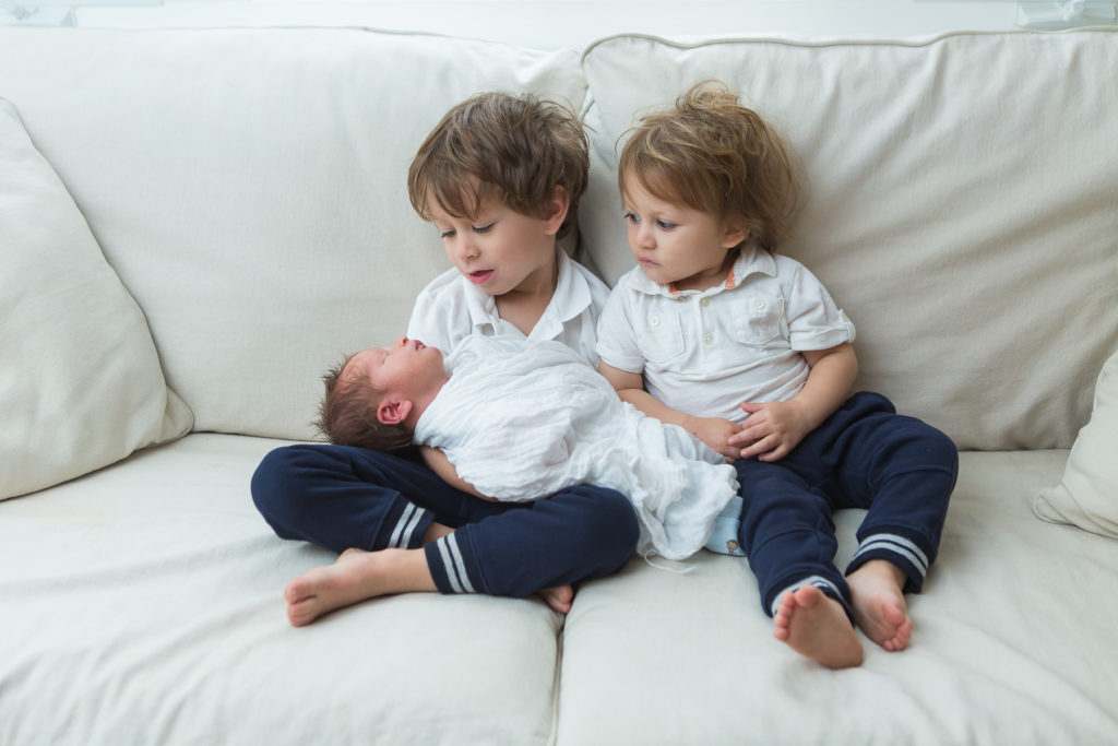 two big brothers holding baby brother