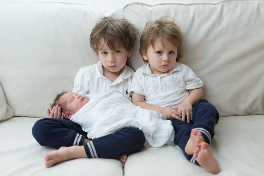 two little boys holding newborn brother