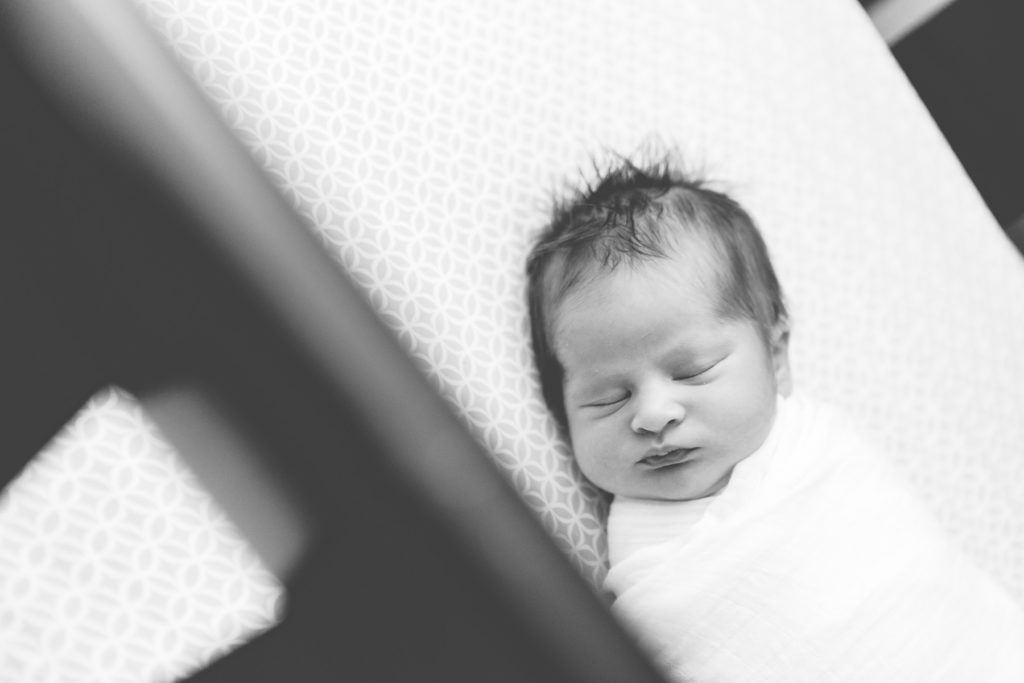 black and white newborn sleeping in crib