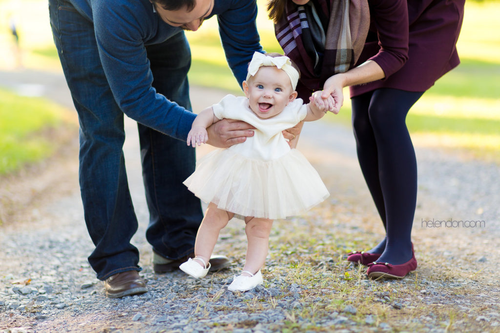 baby laughing holding parents hands