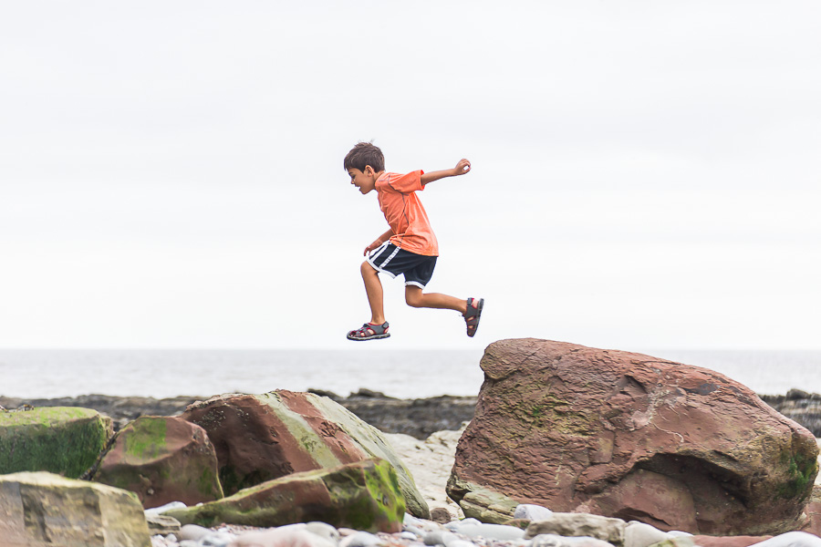 little boy jumping between rocks midair