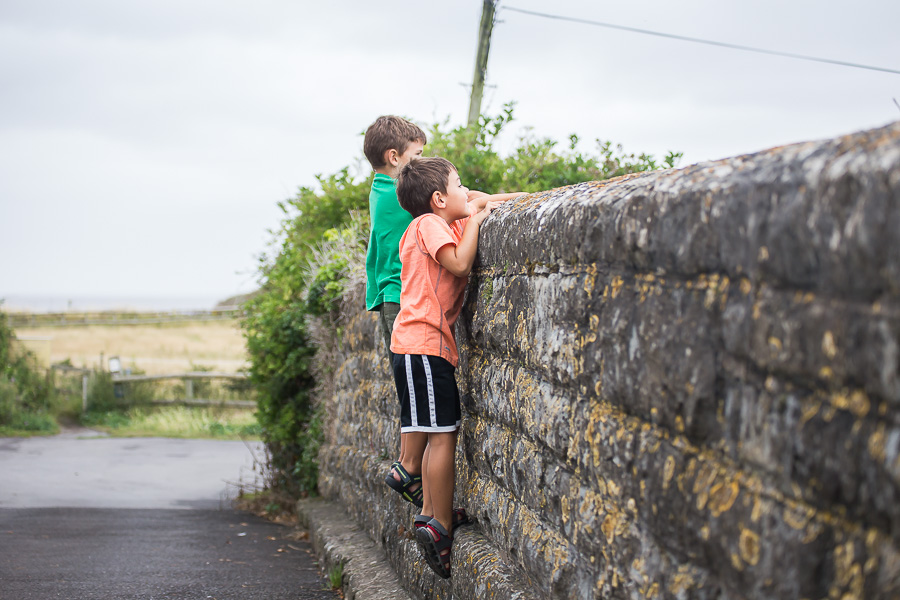 boys hanging on stone wall looking at steam train
