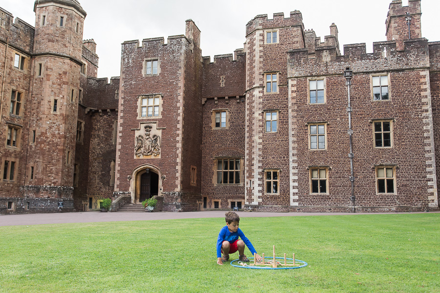 little boy playing on lawn in front of dunster castle