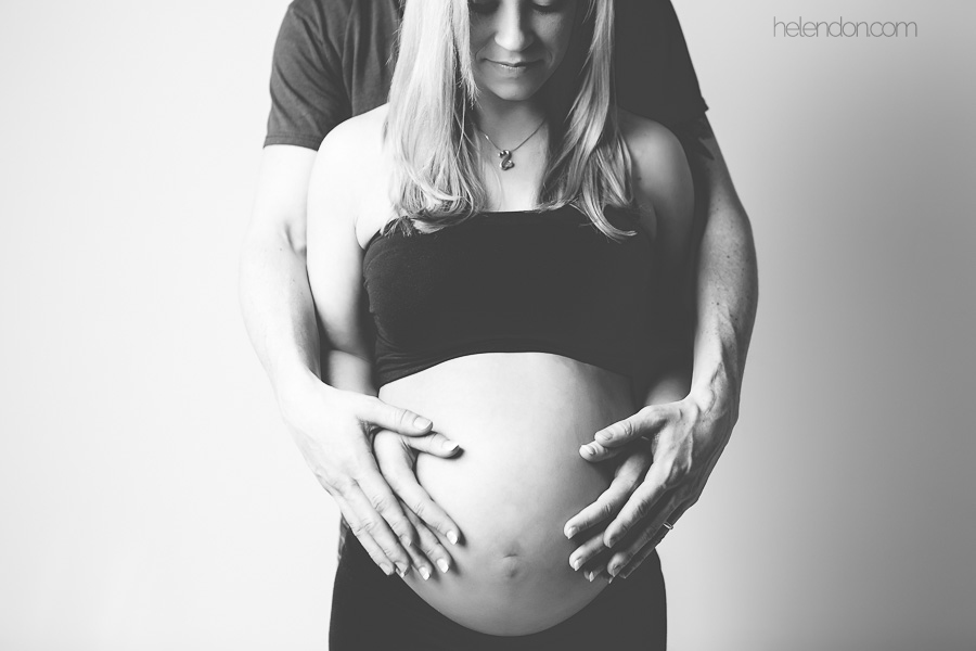 husband and wife hands on pregnant belly