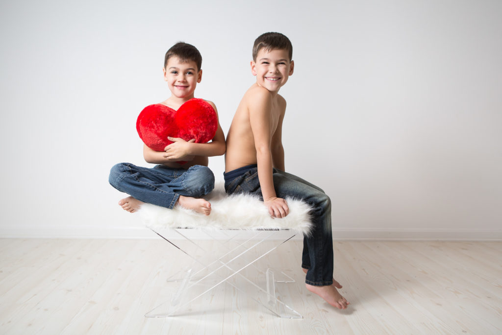 cute young boys sitting on white fur chair