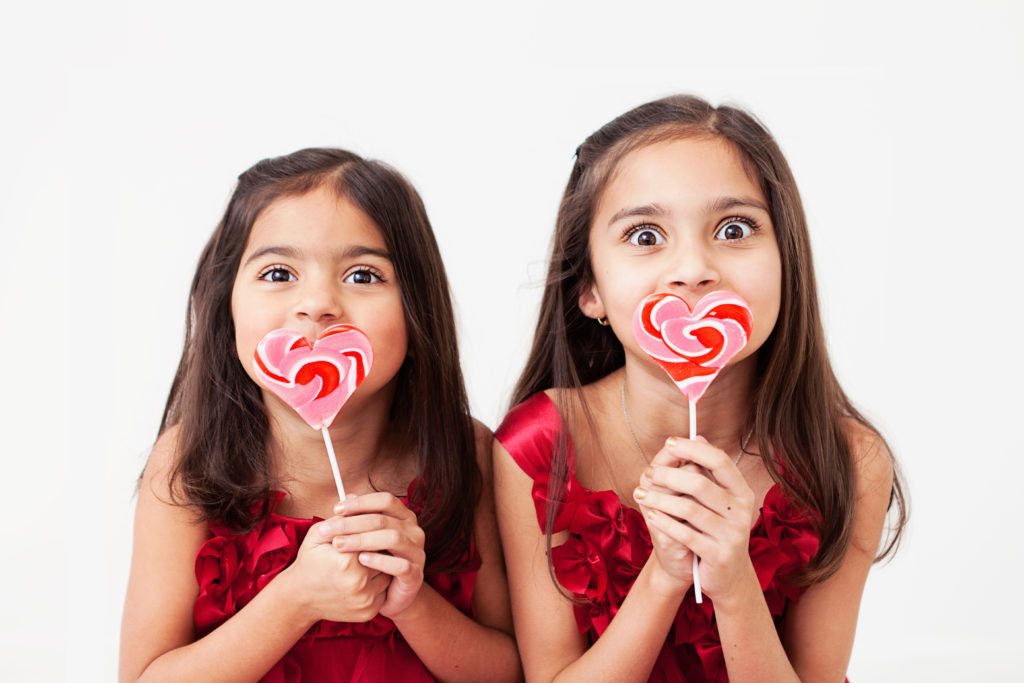 little girls with heart shaped lollipops laughing