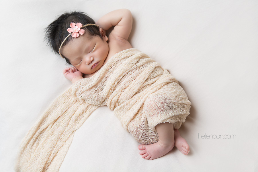 newborn girl sleeping in beige wrap