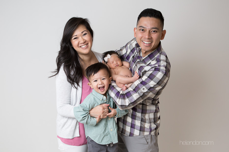 family of four with newborn smiling