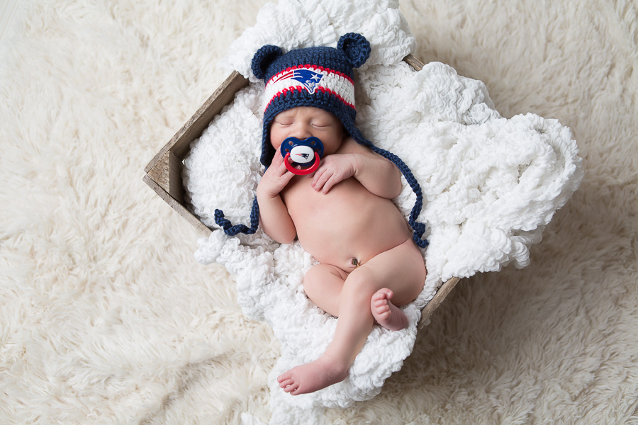 newborn baby with patriots hat and paci