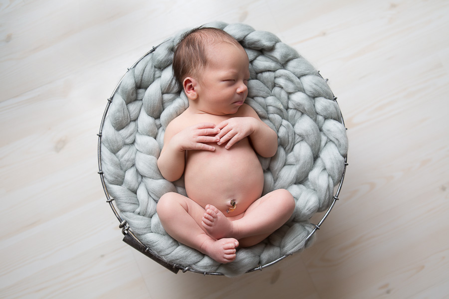 adorable newborn boy sleeping on grey braid