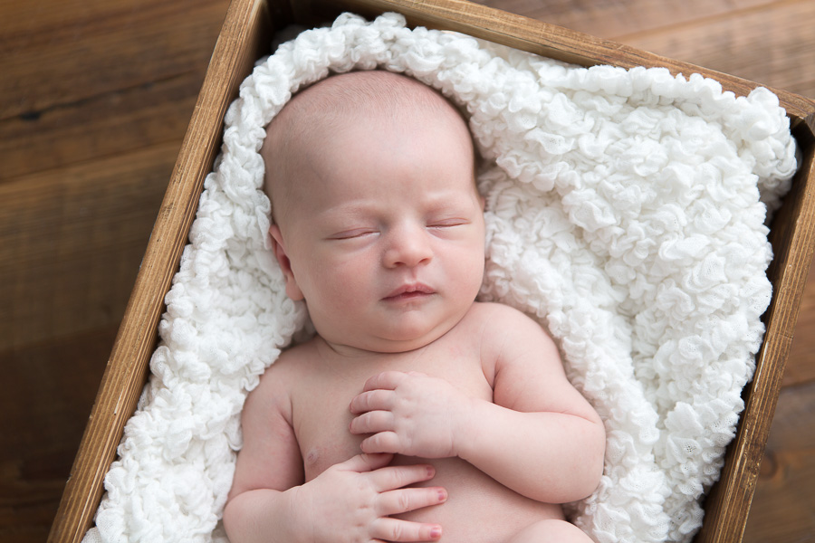 newborn baby sleeping with hands on chest