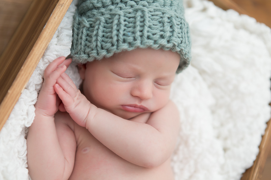 newborn boy sleeping in blue knit hat