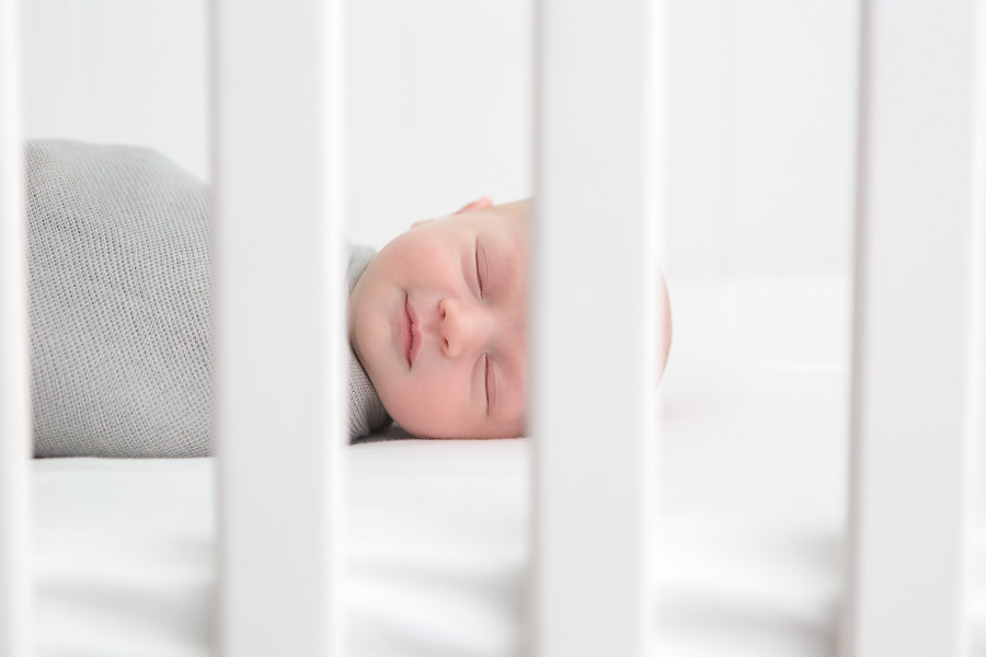 adorable baby boy smiling in sleep in crib