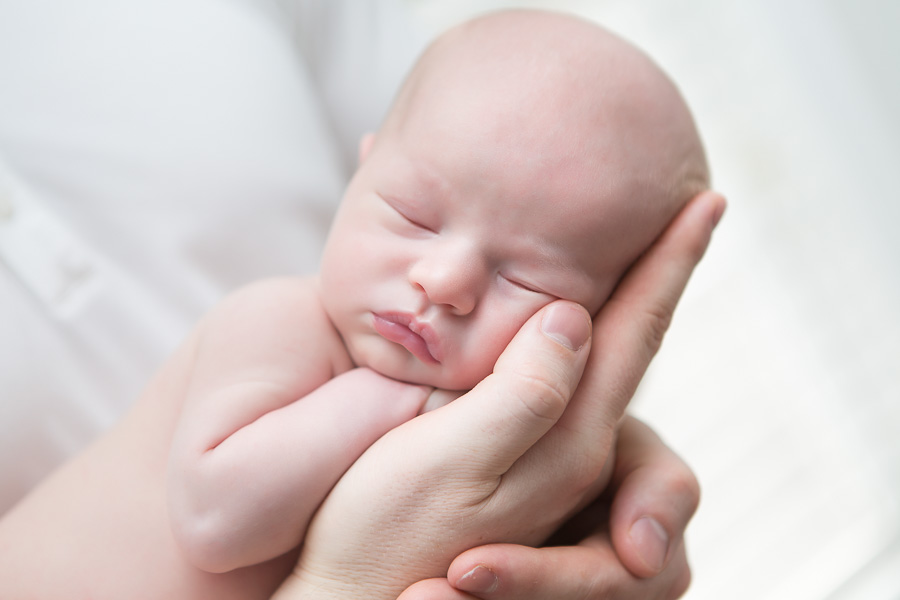 sweet close up of newborn boy sleeping in dads hand