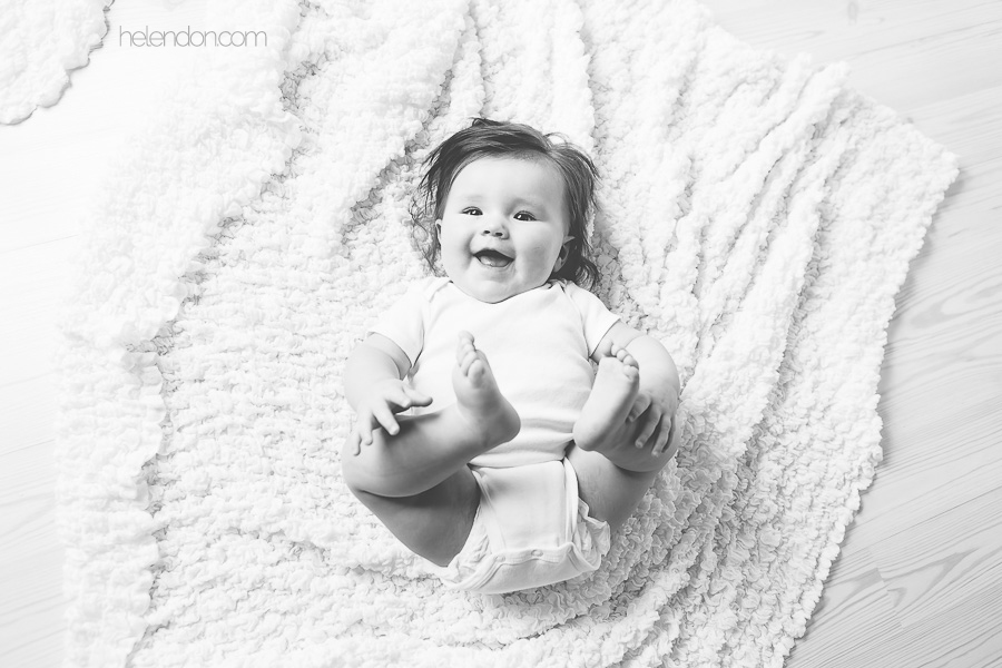 black and white of baby laughing and grabbing feet