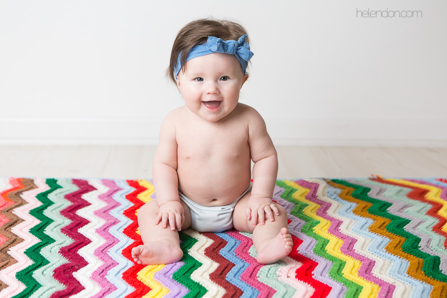 6 month old baby sitting on colorful chevron blanket