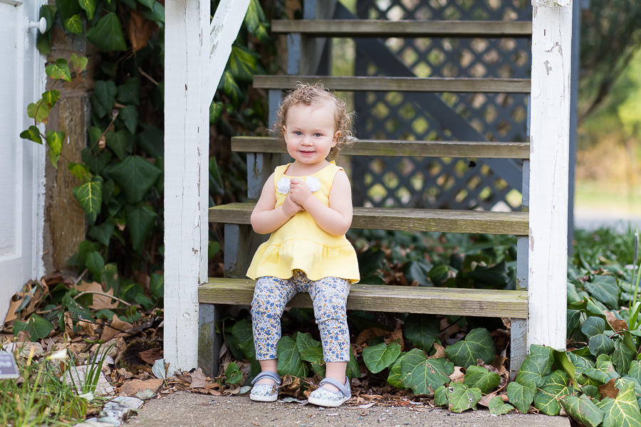 one year old sitting on steps smiling
