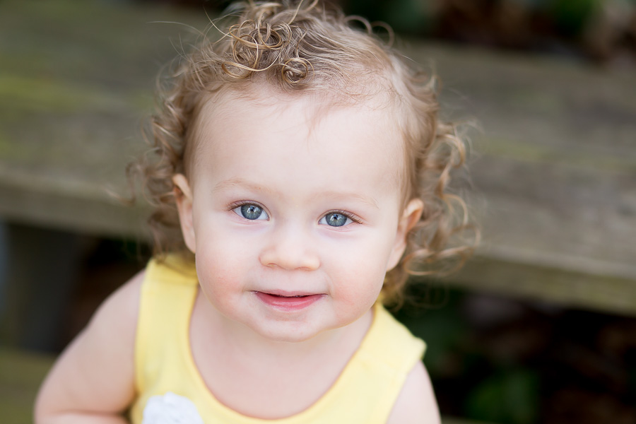one year old with curly hair smiling portait