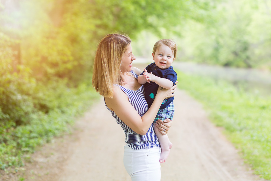 outdoor portrait of mom holding son laughing with sunflare 