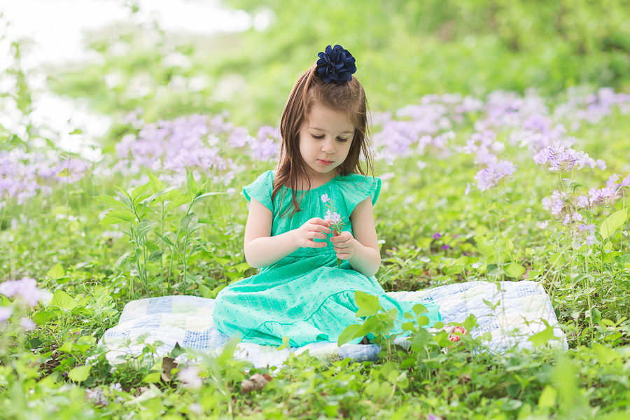 little girl in green dress sitting in purple flowers