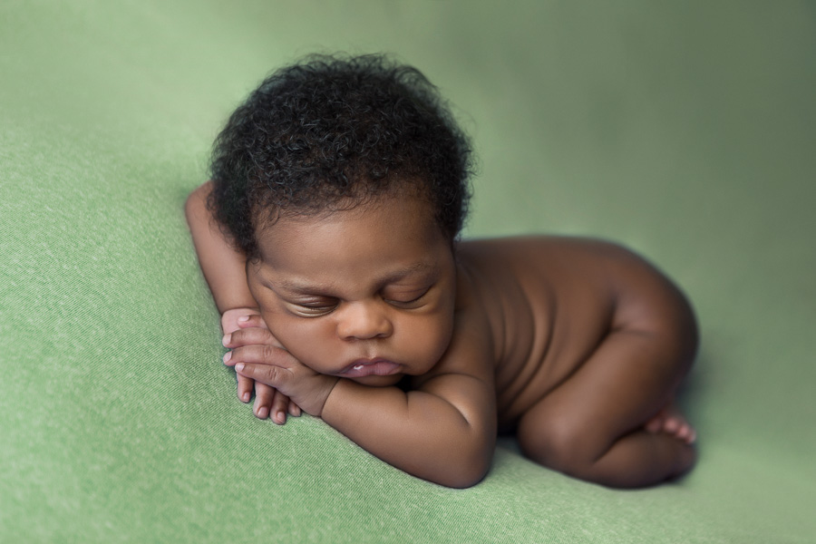 african american newborn sleeping on green blanket