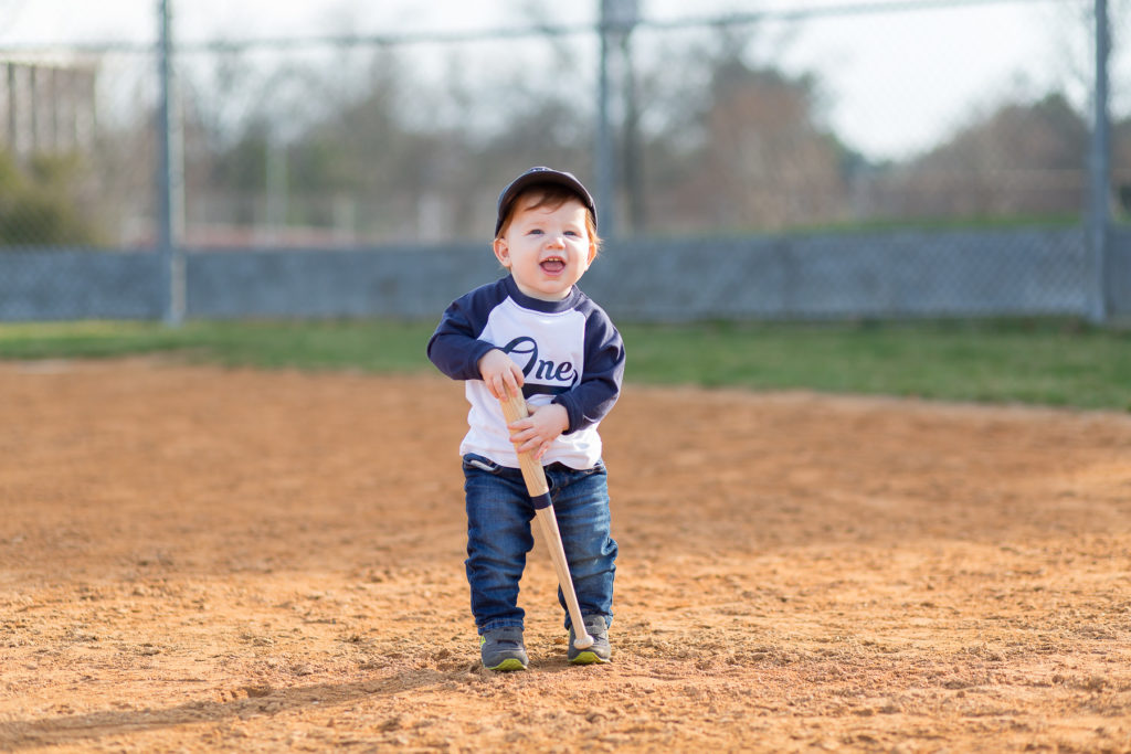 one year old boy holding baseball bat smiling