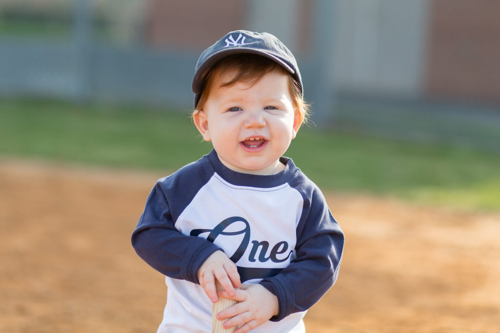 one year old in baseball hat laughing